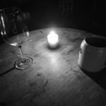 Grimdark Fantasy Stimmung. Alter Tisch mit Kerze, Krug und Glas. Schwarz Weiß. Aethels Taverne.