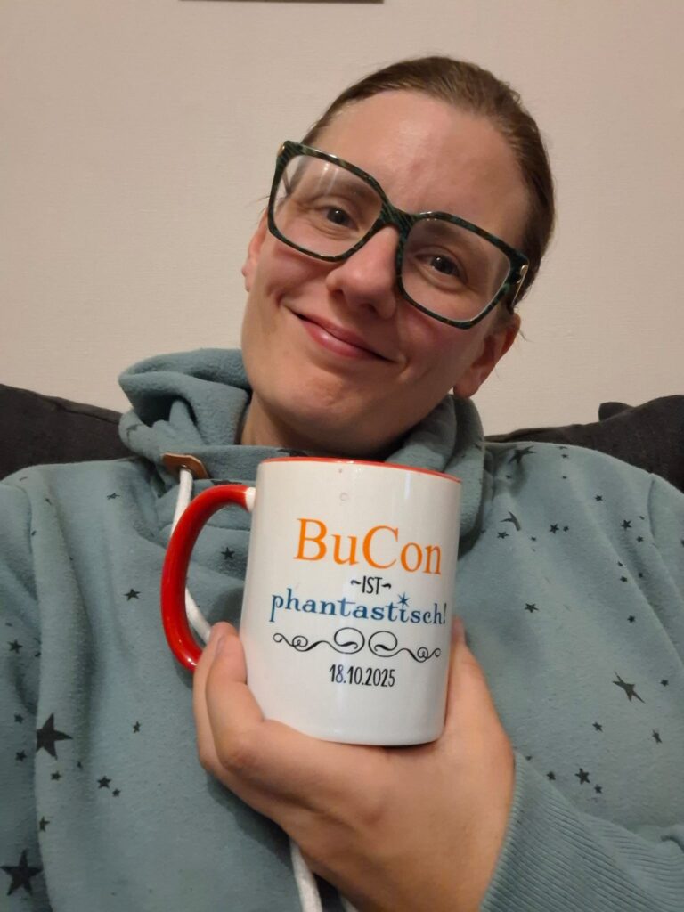 Glückliche Autorin Eva von Kalm mit ihrer BuCon 2025 Tasse
