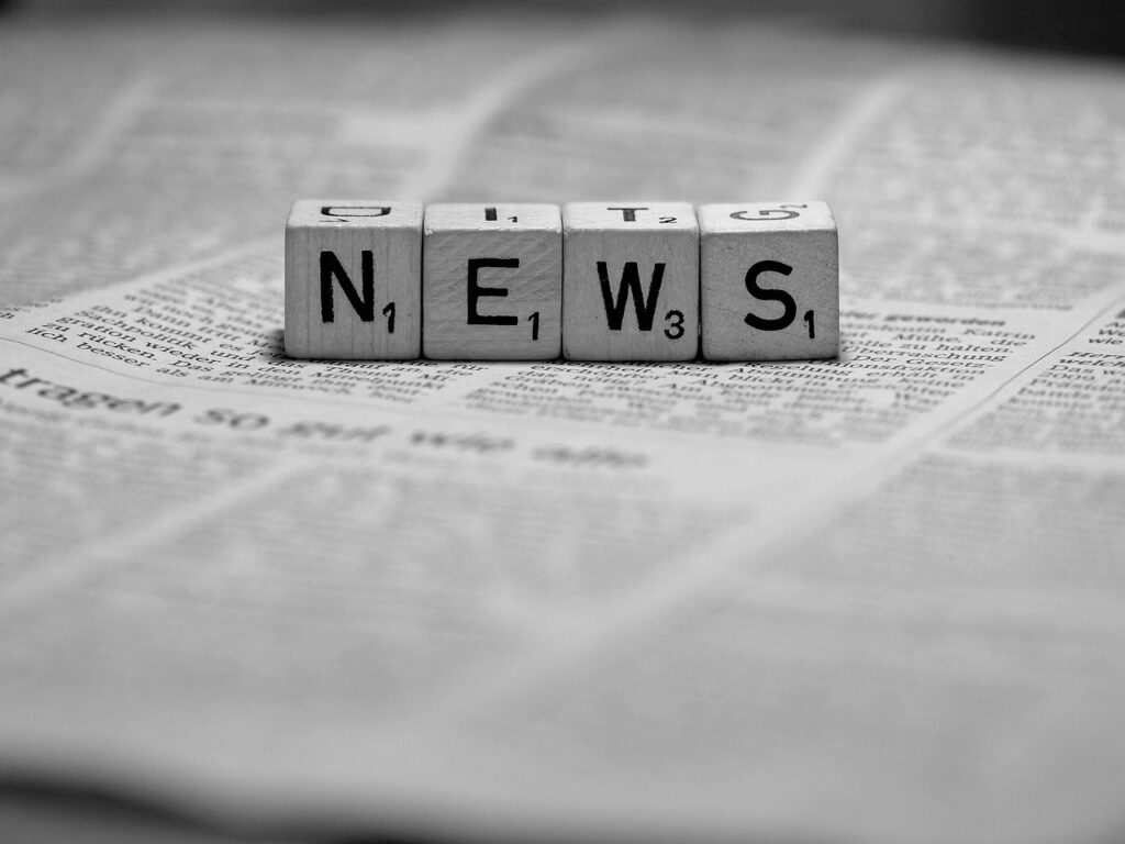 Zeitung mit Buchstabenwürfeln NEWS darauf liegend, schwarz weiß